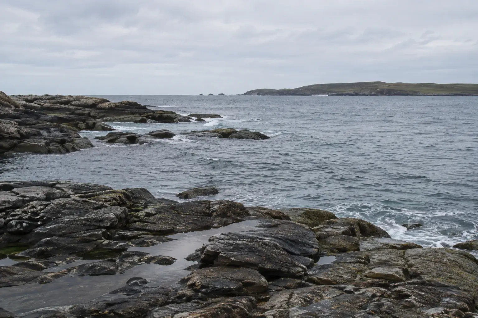 Rocky coastline with fine water texture and a soft overcast sky